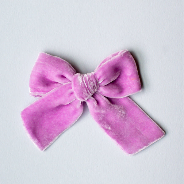 A dusty pink hand-dyed velvet bow on a white background.