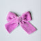 A dusty pink hand-dyed velvet bow on a white background.