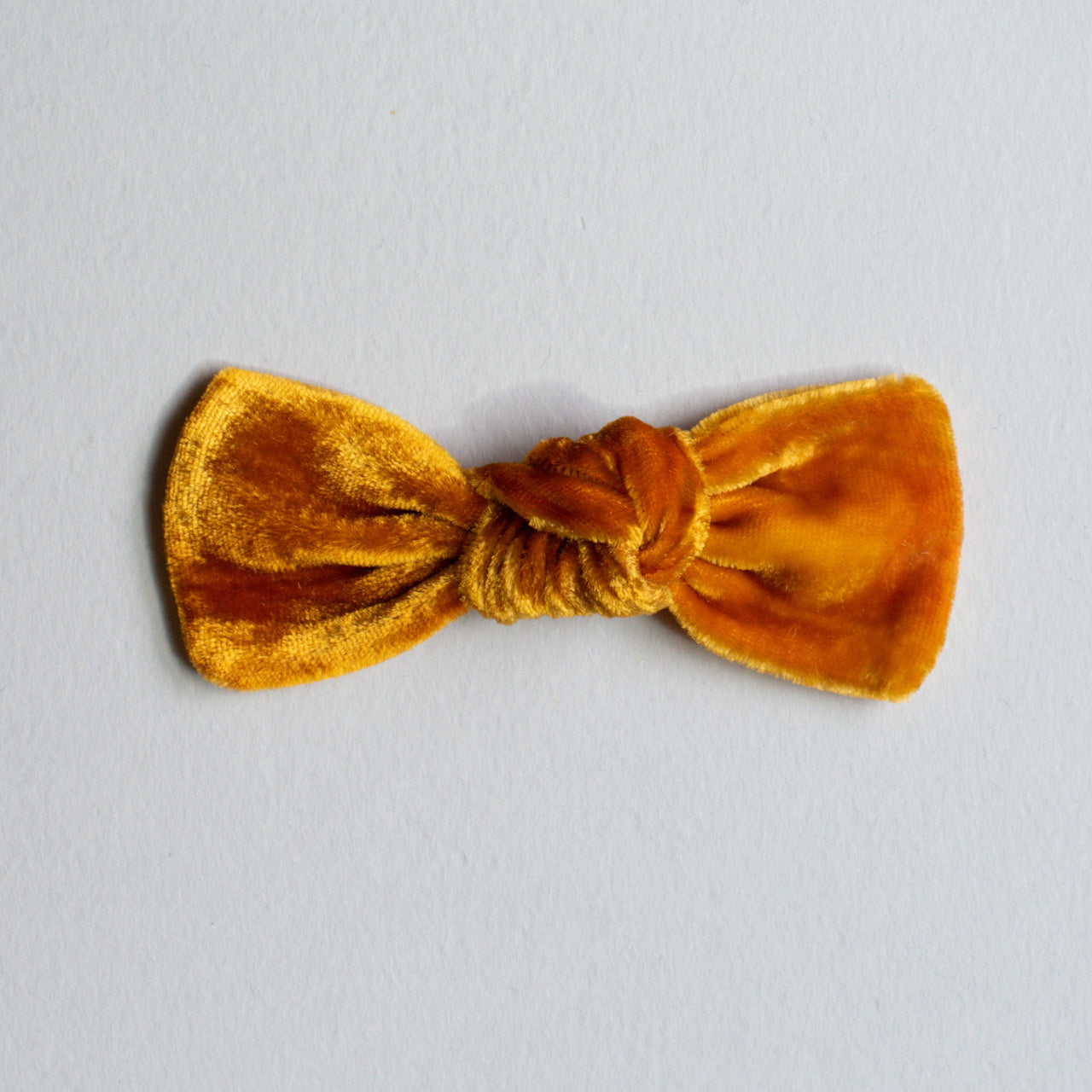 A hand-dyed velvet bow in a caramel color, displayed on a white background.