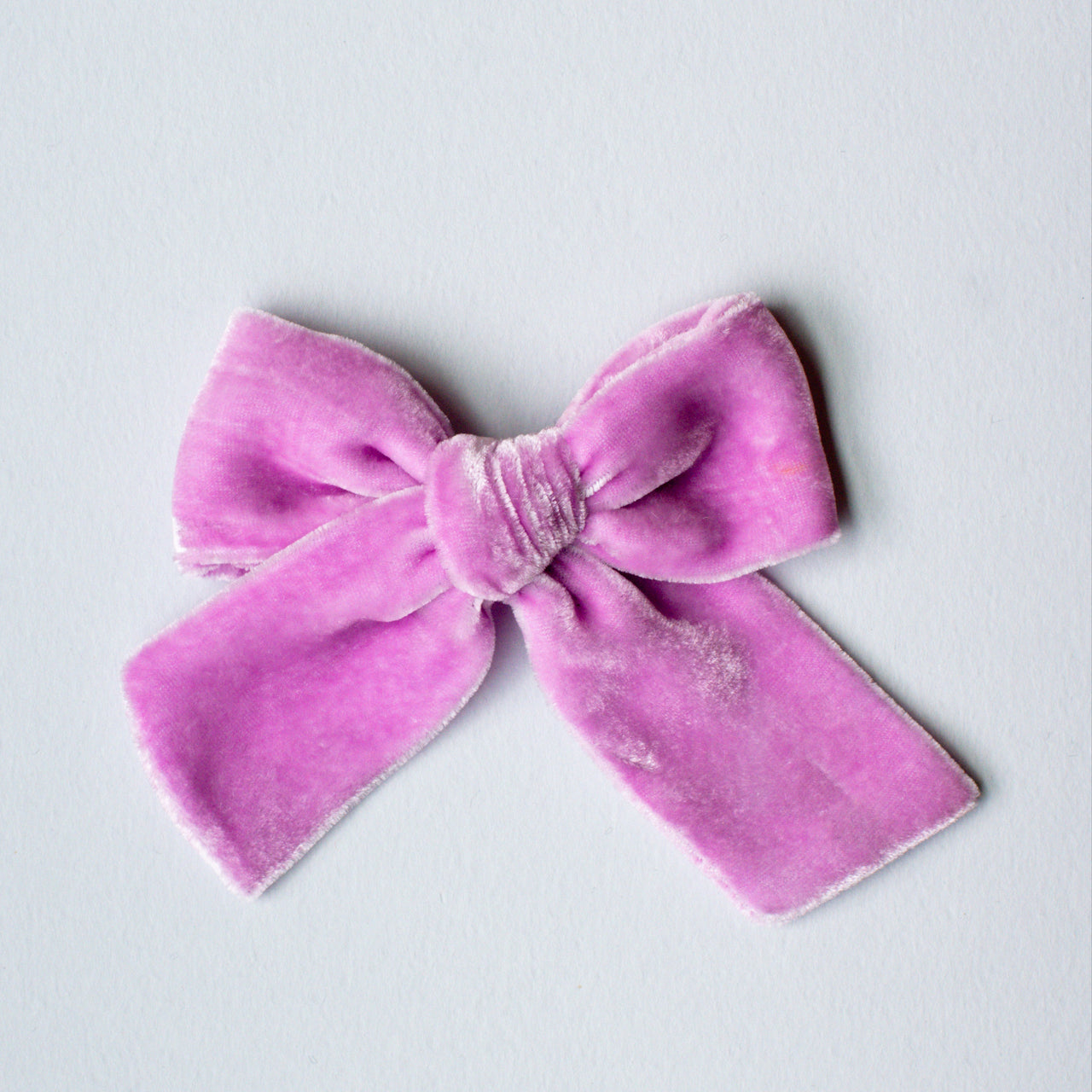 A dusty pink hand-dyed velvet bow on a white background.