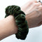 Green velvet scrunchie on a wrist against a white background